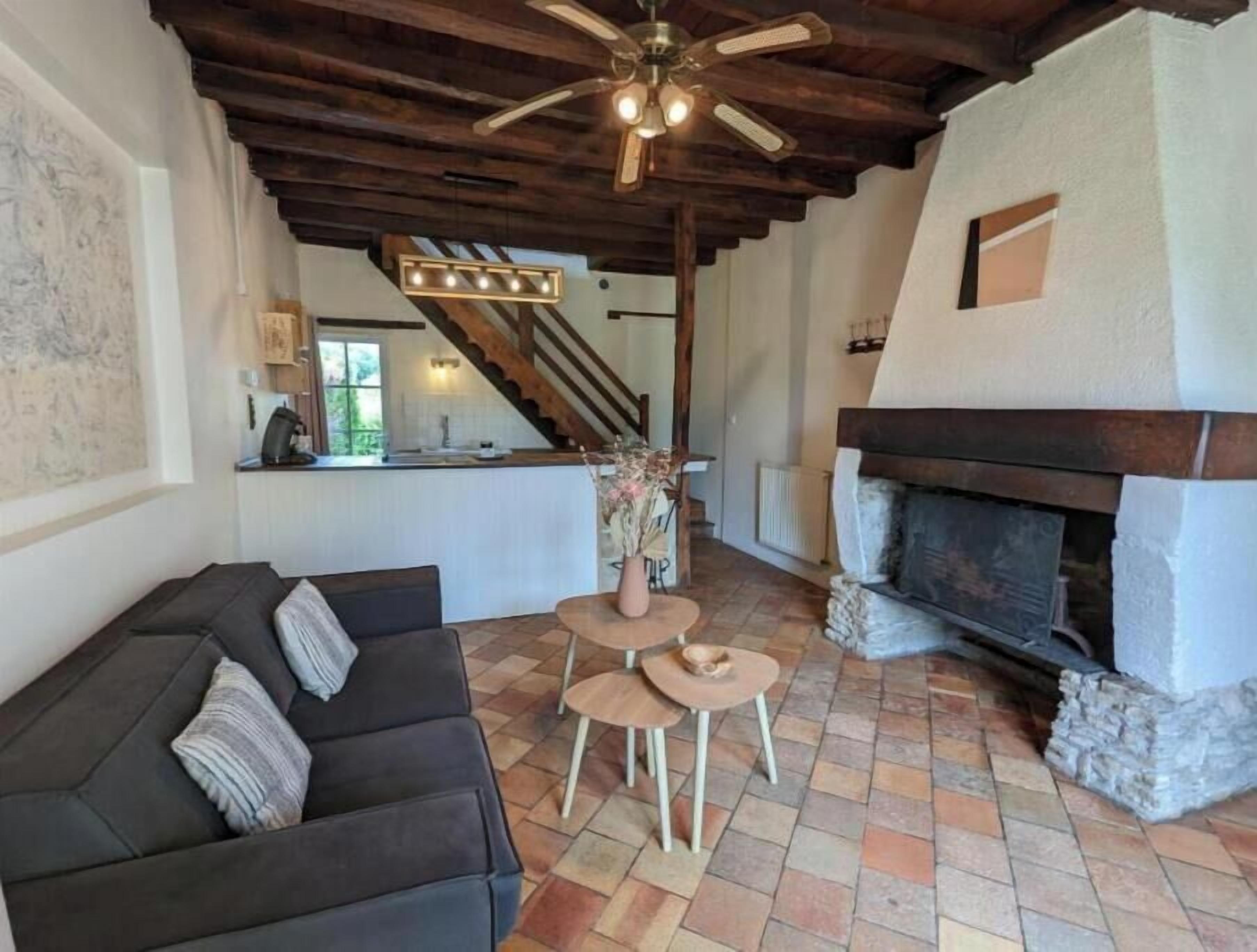 Un salon chaleureux avec une cheminée, un canapé, un coin repas et un escalier menant à l’étage supérieur.