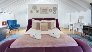 Una camera da letto con un letto grande, una poltrona blu, una scrivania e un lampadario.