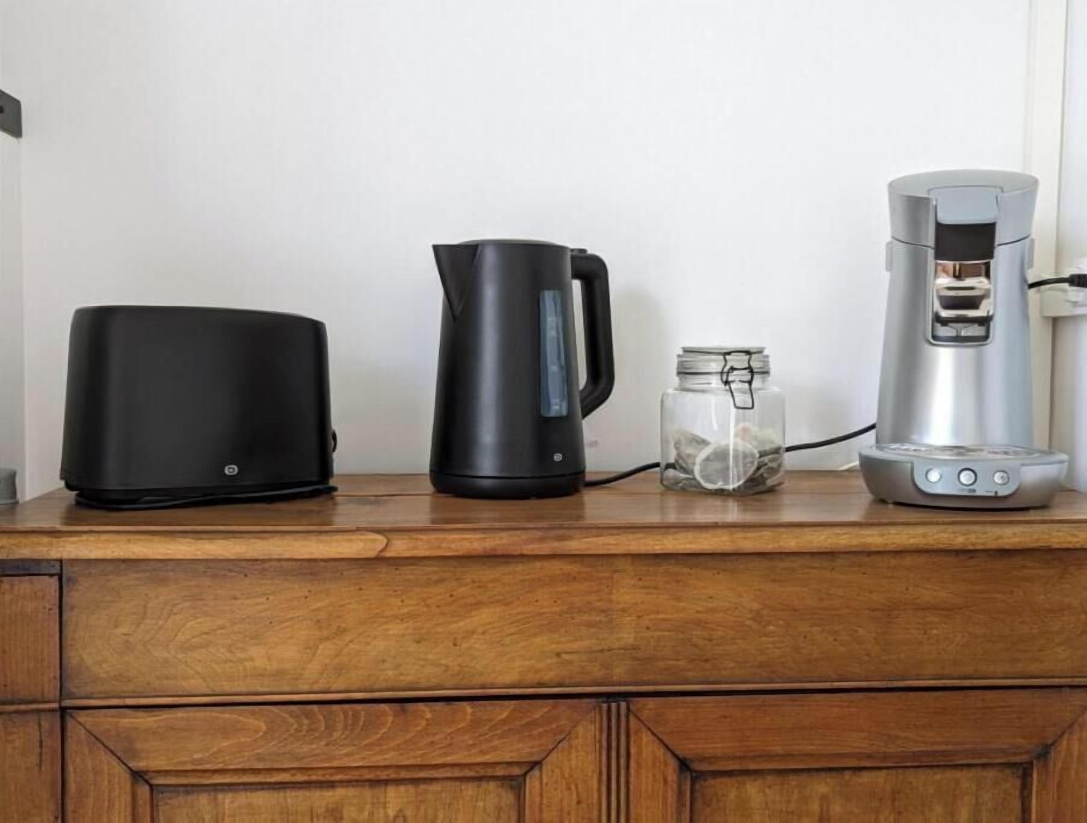 A kitchen counter with a coffee maker, a kettle, and a toaster.
