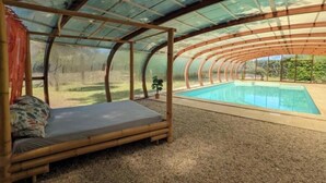 Una habitación con techo curvo, una cama y una piscina.