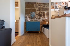 Ein Zimmer mit einer Steinwand, einem blauen Kommode, einem weißen Schrank und Holzboden.