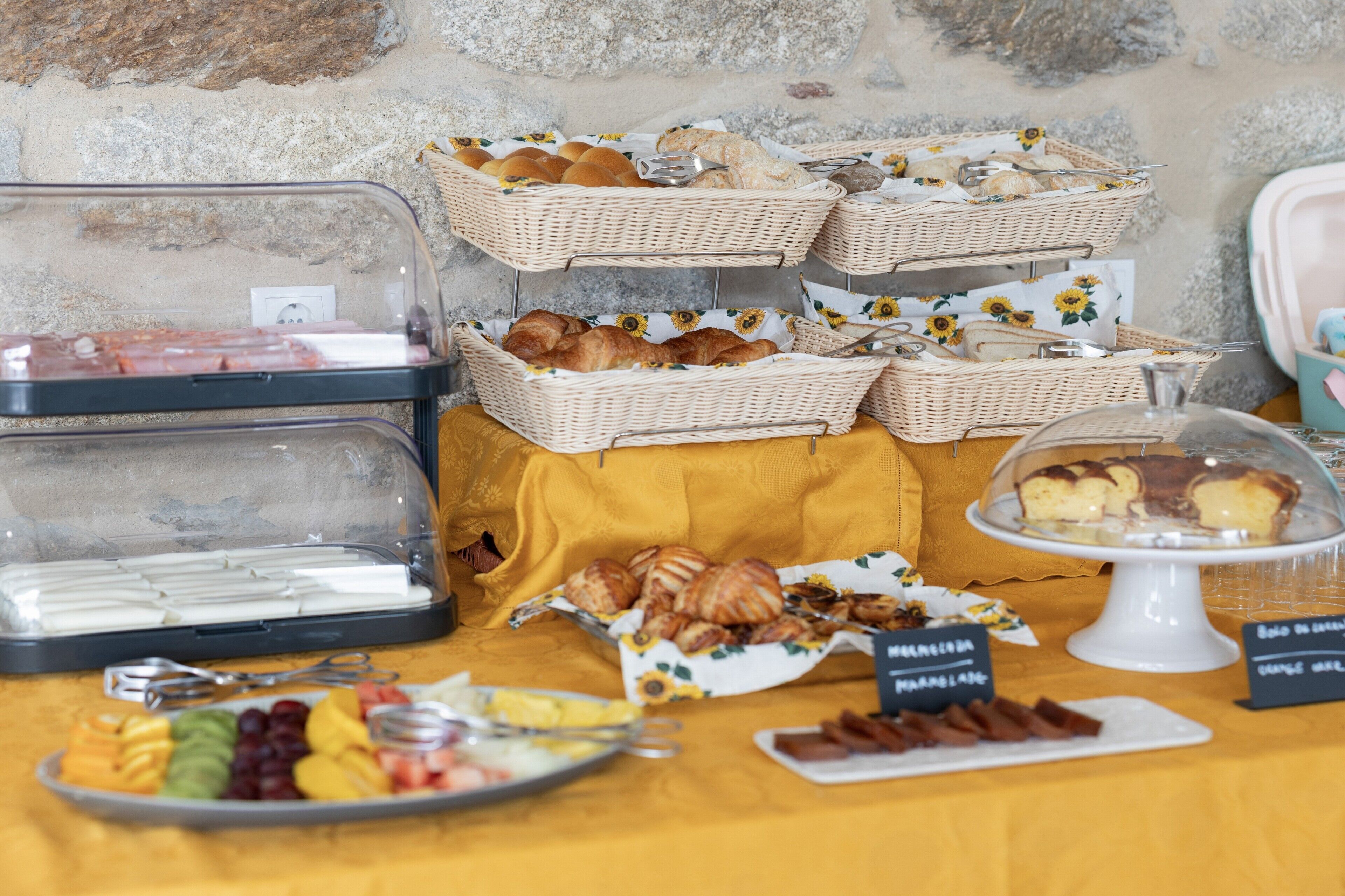 A buffet table with various food items, including fruits, pastries, and a cake display.
