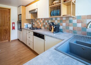 A kitchen with a built-in dishwasher, a stove, and a coffee maker. - Oaks Lodge Cottage (Ambleside)
