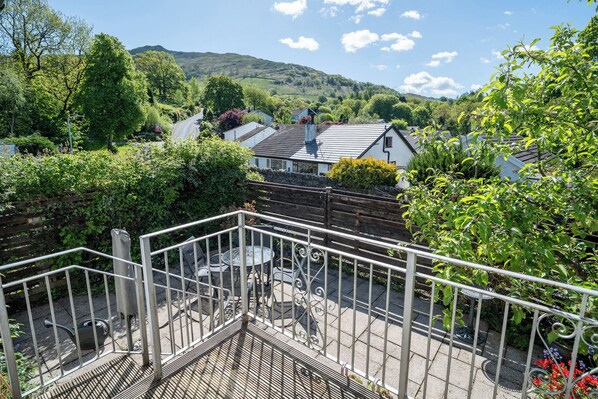 A balcony with a view of a village, a metal railing, and a table with chairs. - Oaks Lodge Cottage (Ambleside)