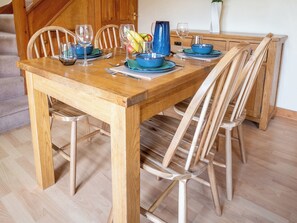A wooden dining table set with blue plates, glasses, and a pitcher, surrounded by wooden chairs. - Oaks Lodge Cottage (Ambleside)