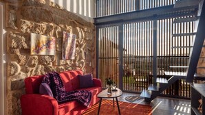 A modern interior with a stone wall, red sofa, artwork, and a view through a metal gate.
