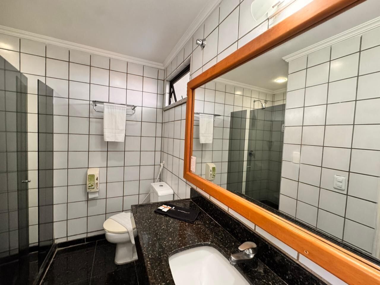 A bathroom with a toilet, sink, mirror, and tiled walls.