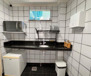 A compact kitchen with a microwave, sink, and storage shelves. - Villa Nautilus by Be Happy (Fortaleza)