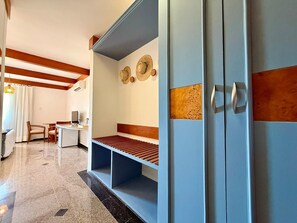 Una camera d'albergo con un letto, una scrivania, una sedia e un armadio.