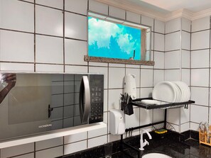 Una cucina con un forno a microonde, un espositore per piatti e una finestra vista cielo.