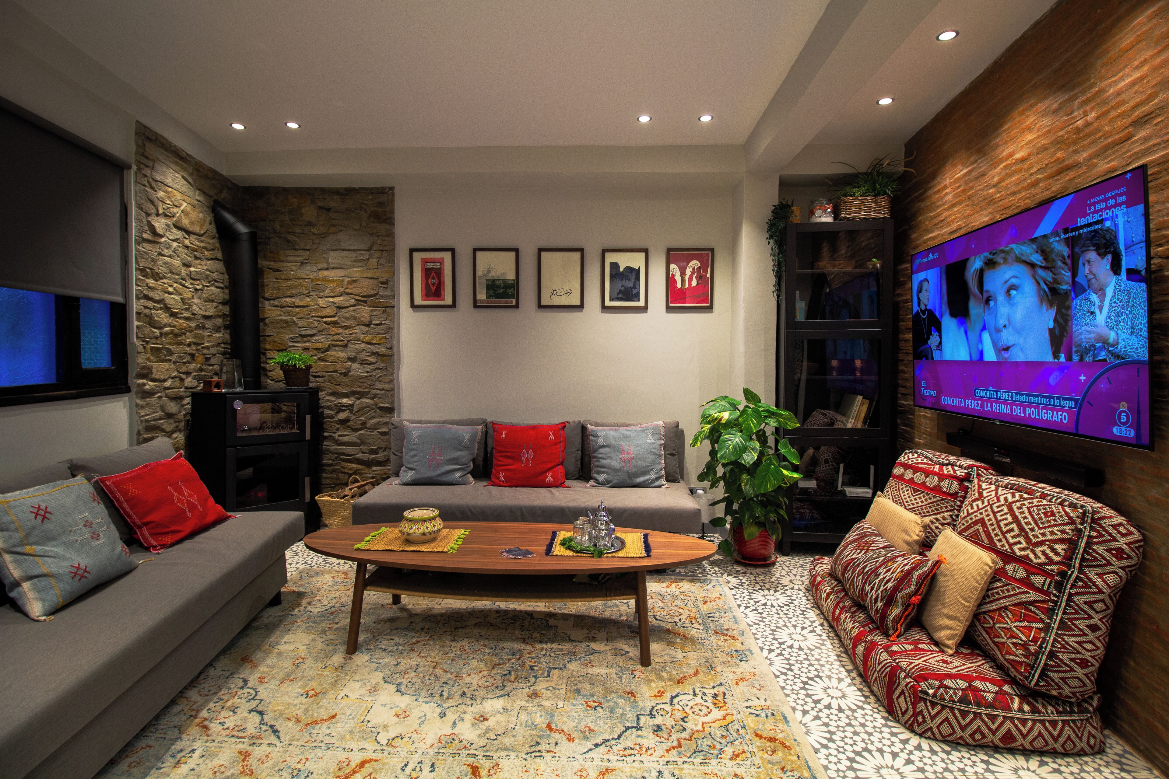 Una sala de estar con un sofá, una mesa de centro, un televisor y cuadros en la pared.