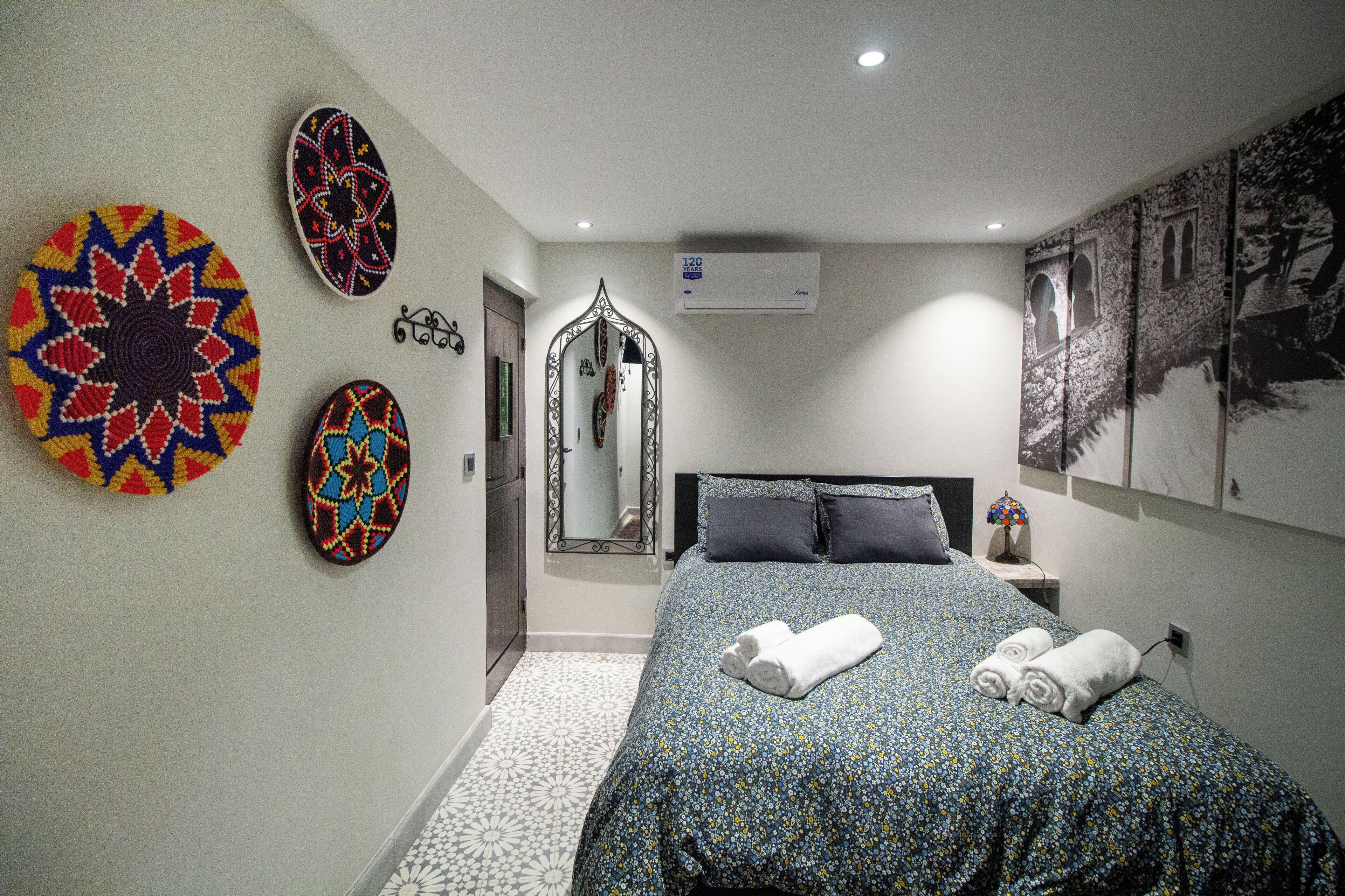 Une chambre à coucher avec un lit, un miroir et des œuvres d’art décoratives au mur.
