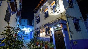 A narrow street with buildings on either side, featuring balconies and a cobblestone path.