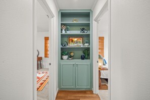 Ein Korridor mit einem grünen Schrank, der verschiedene dekorative Gegenstände und ein gerahmtes Bild enthält.