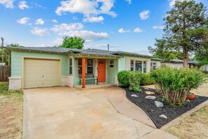 Ein eingeschossiges Haus mit Garage, Veranda und einem gepflegten Garten.