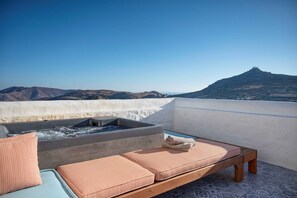 A rooftop terrace with a hot tub, lounge chairs, and a view of a mountain. - Villa Chora with sea and sunset view (Patmos)