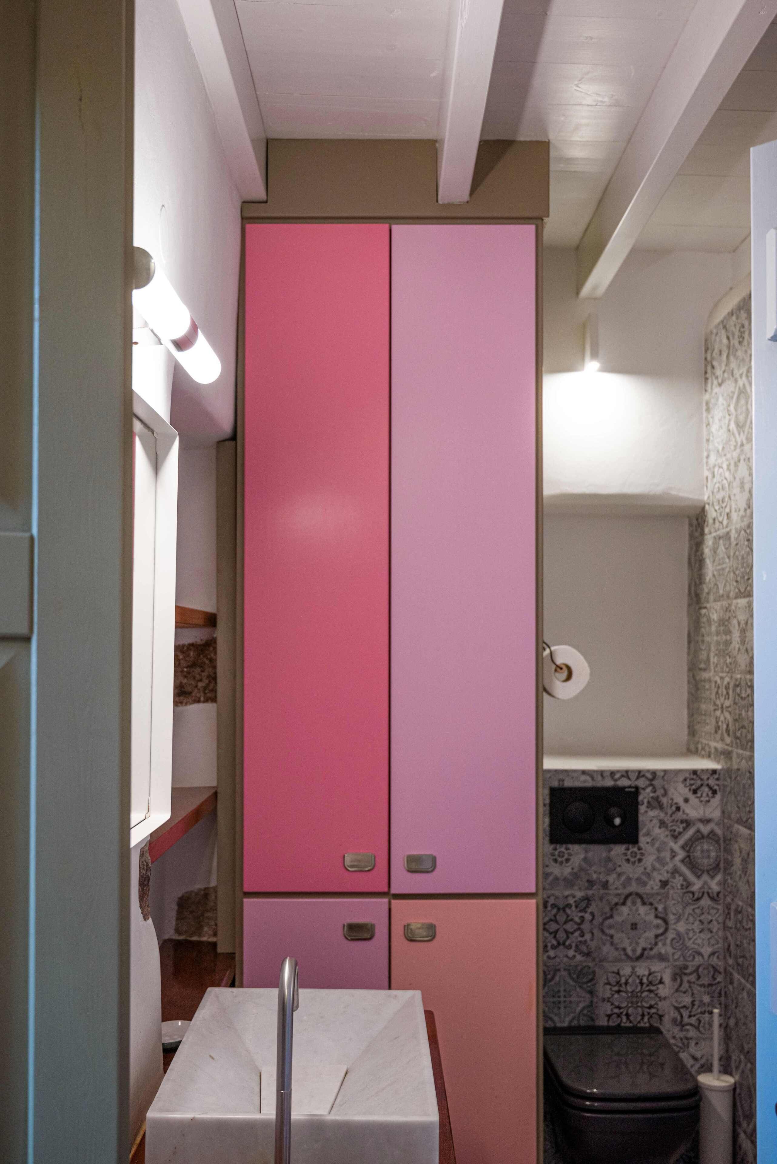 Ein Badezimmer mit einem rosa Schrank, einer Toilette und einem Waschbecken.
