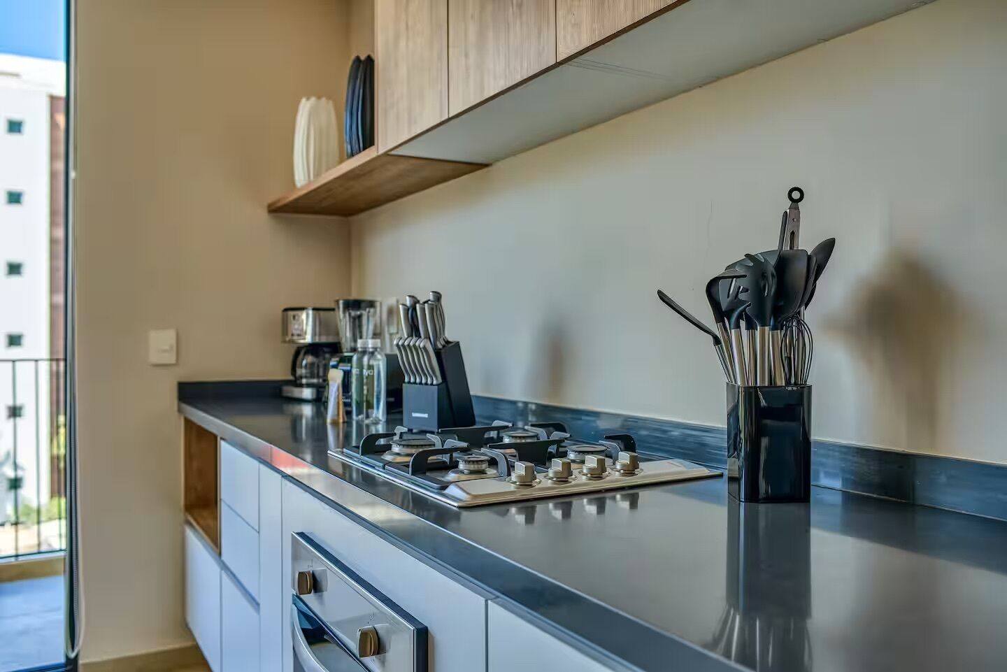 A modern kitchen with a gas stove, stainless steel appliances, and a coffee maker.