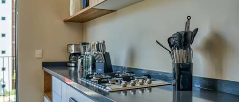 A modern kitchen with a gas stove, stainless steel appliances, and a coffee maker.