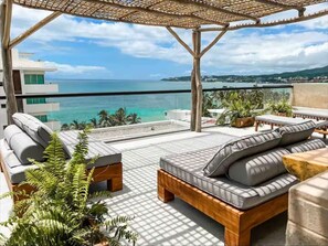 A balcony with a view of the ocean, a wooden pergola, and outdoor seating. - Arenka (Bucerías)