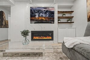 Ein modernes Wohnzimmer mit Flachbildfernseher, Kamin und Sofa.
