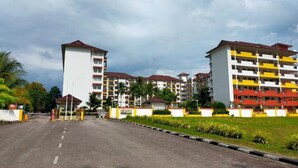 A multi-story residential building with a central courtyard, a gated entrance, and a road leading to it. - Homestay Ziyan with pool near beach (Port Dickson Town)