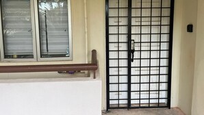 A building entrance with a barred door and a window with blinds. - Homestay Ziyan with pool near beach (Port Dickson Town)