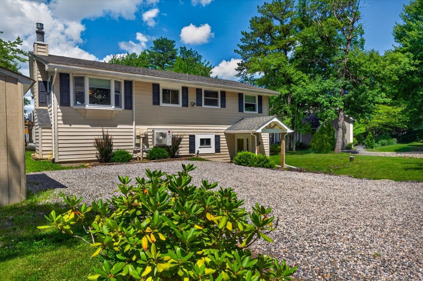 A single-story house with a covered porch, a gravel driveway, and a well-maintained lawn.