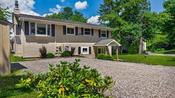 A single-story house with a covered porch, a gravel driveway, and a well-maintained lawn.