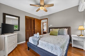 A bedroom with a bed, a television on a dresser, a ceiling fan, and a bedside lamp. - The Bear Creek Lake House: Lake-Front | Kayaks | Fire Pit | Grill | Beach (Jim Thorpe)