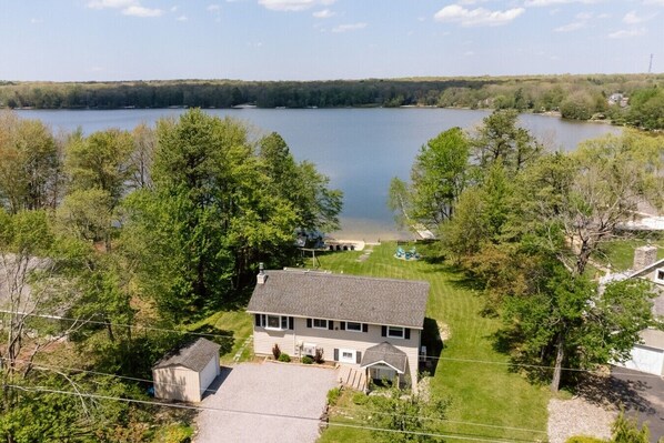 Une maison avec une grande pelouse et vue sur un lac.