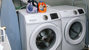 Two white Samsung front-loading washing machines with detergent bottles on top.