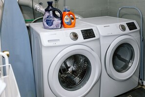 Two white Samsung front-loading washing machines with detergent bottles on top. - The Bear Creek Lake House: Lake-Front | Kayaks | Fire Pit | Grill | Beach (Jim Thorpe)