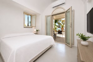 A bedroom with a bed, a bedside table, a lamp, a potted plant, and a sliding glass door leading to an outdoor area. - Villa Flaminia by My Villa Collection (Capri)