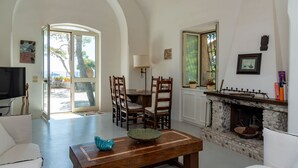A living room with a fireplace, a dining area with chairs, a sofa, and a television. - Villa Flaminia by My Villa Collection (Capri)