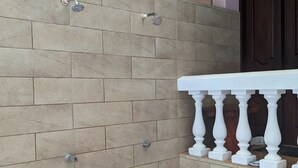 A corner shower with beige tiles, a white balustrade, and a dark wooden door. - Walk to Secluded Playa Azul, Private Pool, 4 Ocean-view Bedrooms, sleeps 8 (Guanacaste Province)