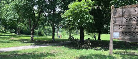 Un parque con un letrero de madera, árboles y un sendero para caminar.