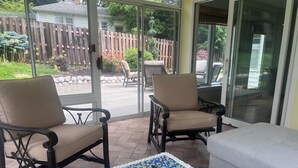 A patio with two chairs, a table with a mosaic top, and a sliding glass door leading to a backyard. - Home on edge of Omaha Regency - 3-bedrooms 1.5 bath (Omaha)