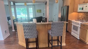 A kitchen with a wooden island, two bar stools, a refrigerator, and a microwave. - Home on edge of Omaha Regency - 3-bedrooms 1.5 bath (Omaha)