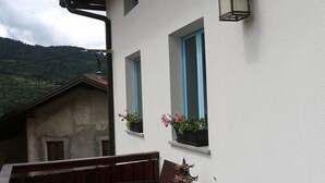 A balcony with wicker furniture, a small table, and potted plants. - Unique Slovene alpine house, within the Soca Valley, close to Most na Soci. (Tolmin)