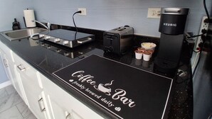 Une cuisine avec un panneau indiquant un coin café, un grille-pain, une bouilloire et un support pour la bouilloire.