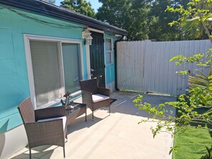 Eine Terrasse mit Korbmöbeln und einer Tür.