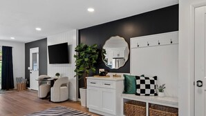 A modern living room with a flat-screen TV, a sofa, a coffee table, a zebra-patterned rug, a large mirror, and a white cabinet with wicker baskets. - Top-Rated Premier Modern Getaway (Petersburg)