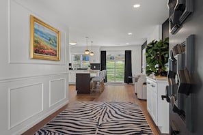 A modern kitchen with a dining area, a zebra-patterned rug, and a large window overlooking a garden.