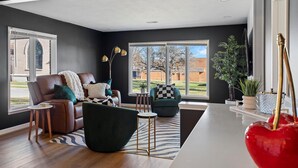 A modern living room with a leather sofa, a green armchair, and a zebra-patterned rug. - Top-Rated Premier Modern Getaway (Petersburg)
