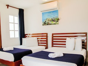 Ein Hotelzimmer mit zwei Betten, einem fensterbelaubten Fenster, einer Klimaanlage und einem Bild an der Wand.