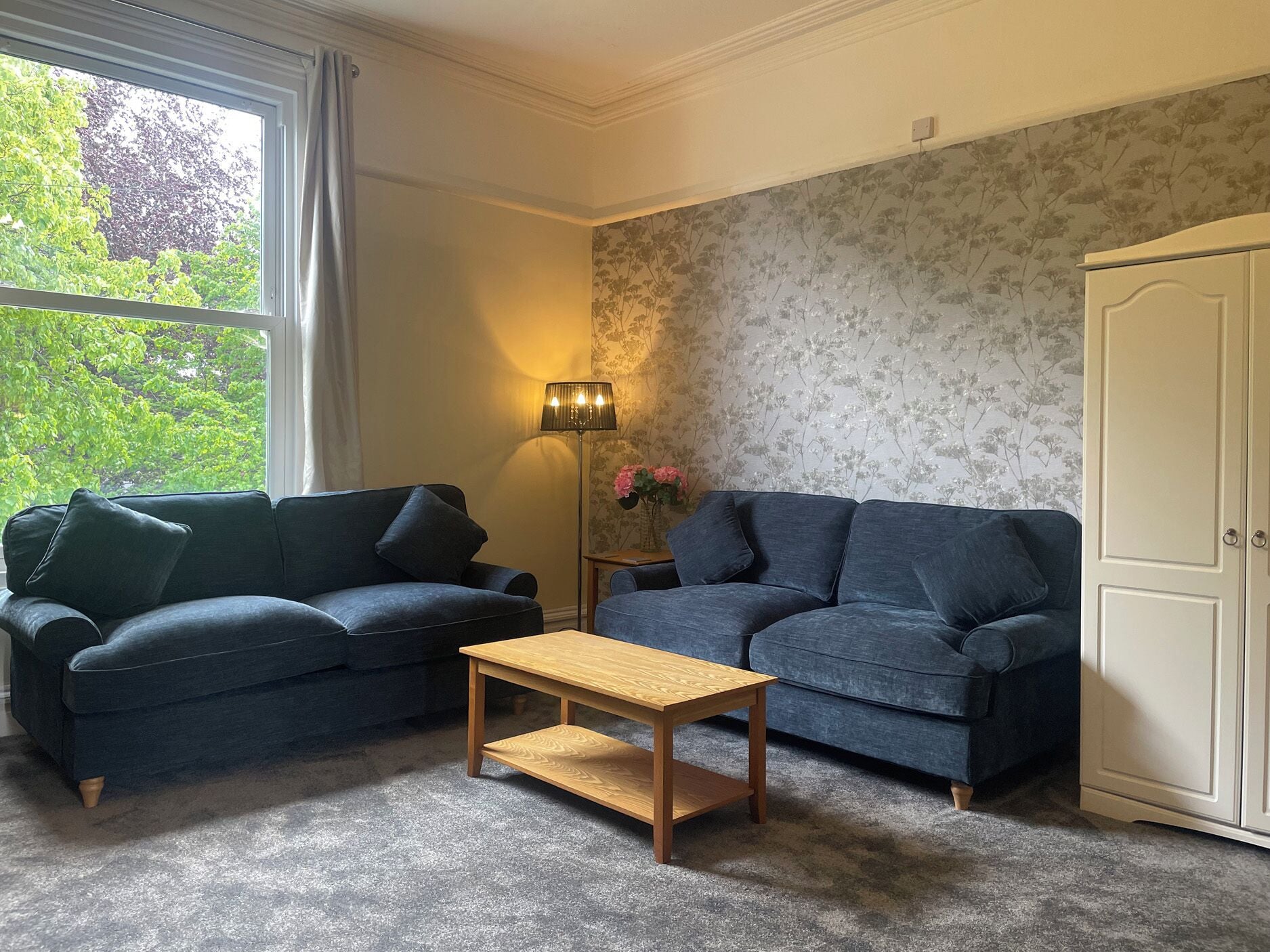A living room with two sofas, a wooden coffee table, a floor lamp, and a wardrobe.