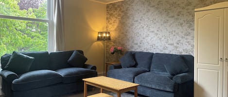 A living room with two sofas, a wooden coffee table, a floor lamp, and a wardrobe.
