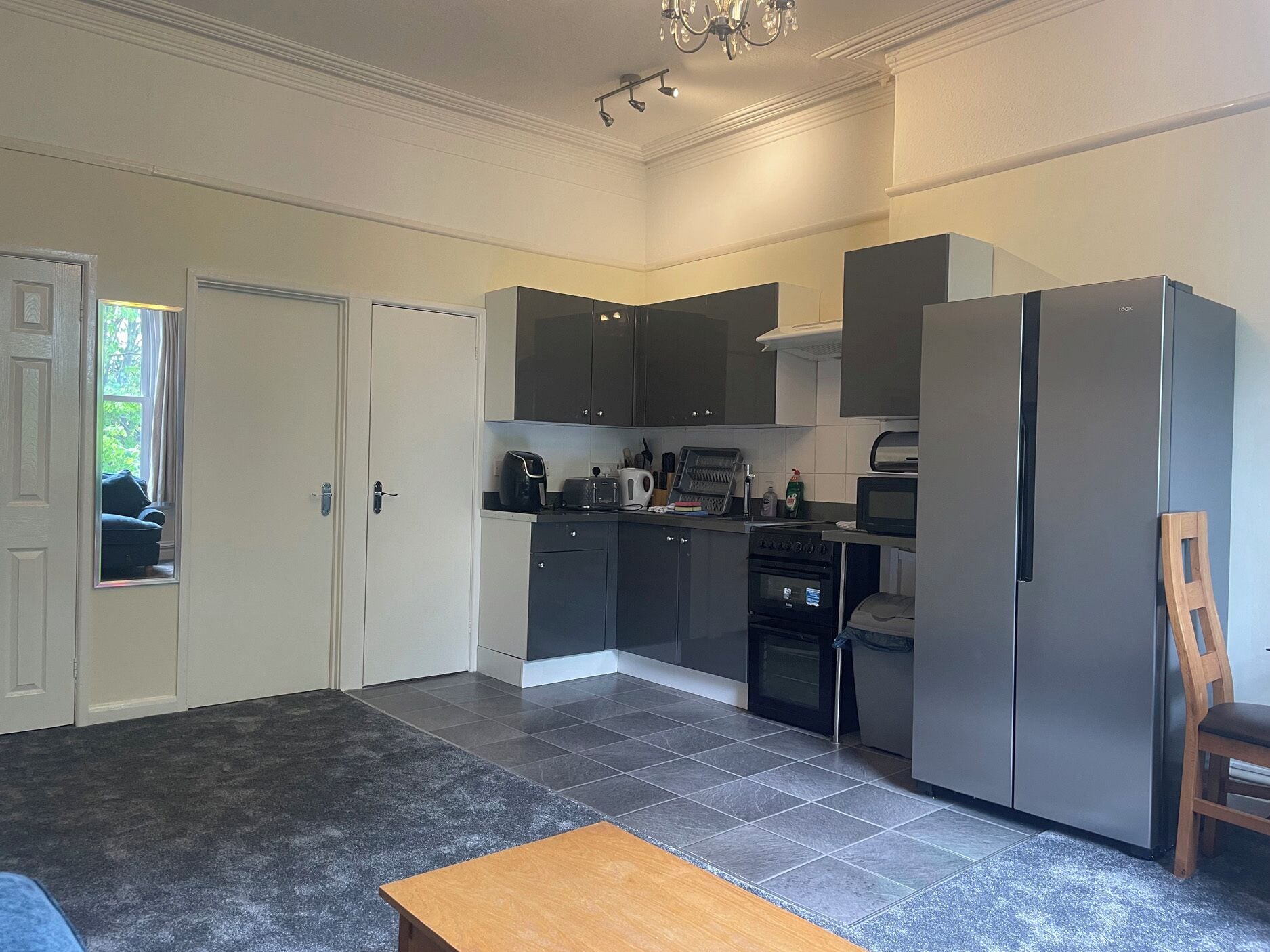 A compact kitchen with dark cabinets, a refrigerator, a microwave, and a toaster.