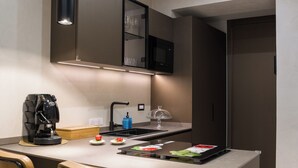 A modern kitchen with a central island, bar stools, pendant lighting, and a microwave. - Aledo Boutique Apartments (Napoli)